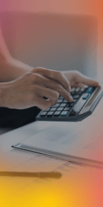 Close-up of hands using a calculator over financial documents with a pen on the desk