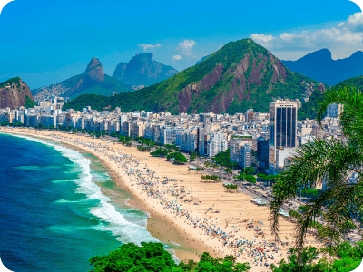 Aerial view of Rio de Janeiro coastline with sandy beach, turquoise sea, high-rise beachfront buildings and green mountains