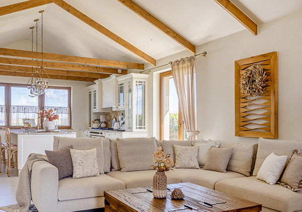 Jasny, przytulny salon z beżową sofą i białą kuchnią w tle