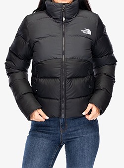 Woman wearing black The North Face insulated puffer jacket with front zip and pockets, styled with blue jeans