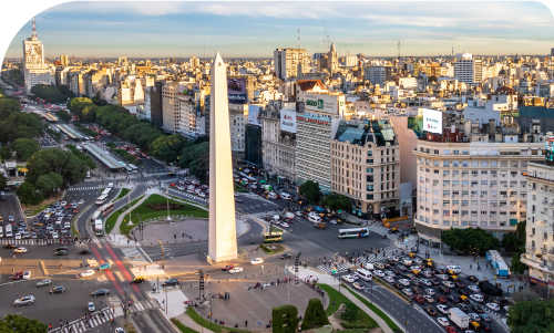 Aerial view of Buenos Aires Obelisk on Avenida 9 de Julio with busy traffic and city skyline at sunset