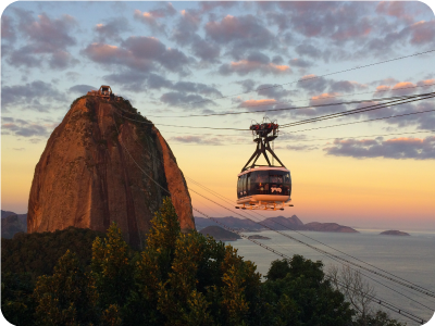 Sunset cable car ascending Sugarloaf Mountain over Guanabara Bay, Rio de Janeiro, with colourful sky and distant islands