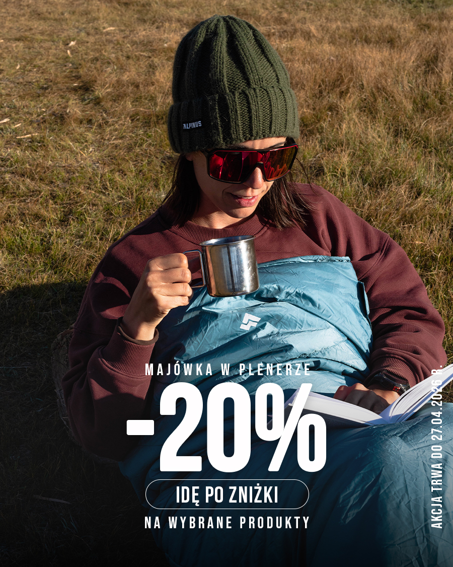 Person in green beanie and red sunglasses wrapped in blue sleeping bag, holding metal mug and reading outdoors; -20% sale overlay