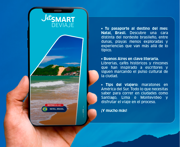 Hand holding smartphone displaying JetSMART Deviaje app showing Natal, Brazil beach; travel tips and Buenos Aires features in sidebar