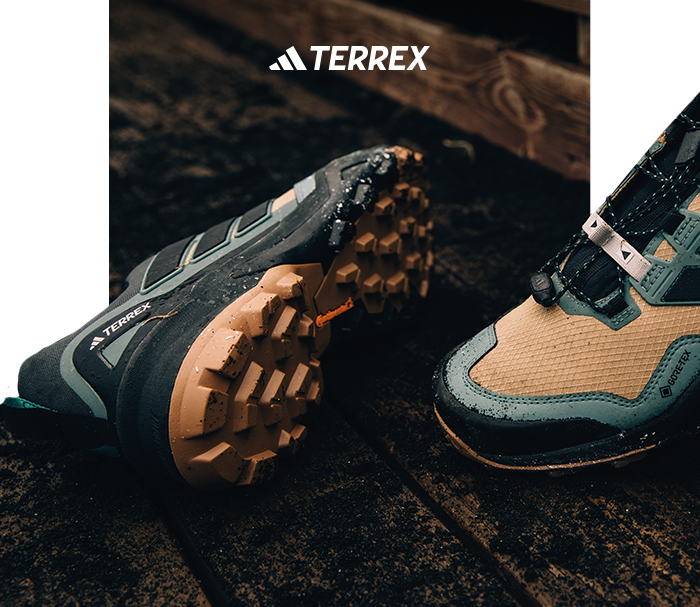 Close-up of Adidas TERREX waterproof trail hiking shoes with mud-speckled lug soles and GORE‑TEX upper