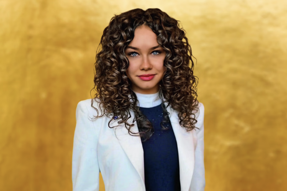 Portret młodej kobiety z brązowymi kręconymi włosami w białej marynarce na złotym tle