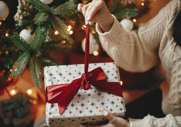 Kobieta rozpakowuje świąteczny prezent przy choince