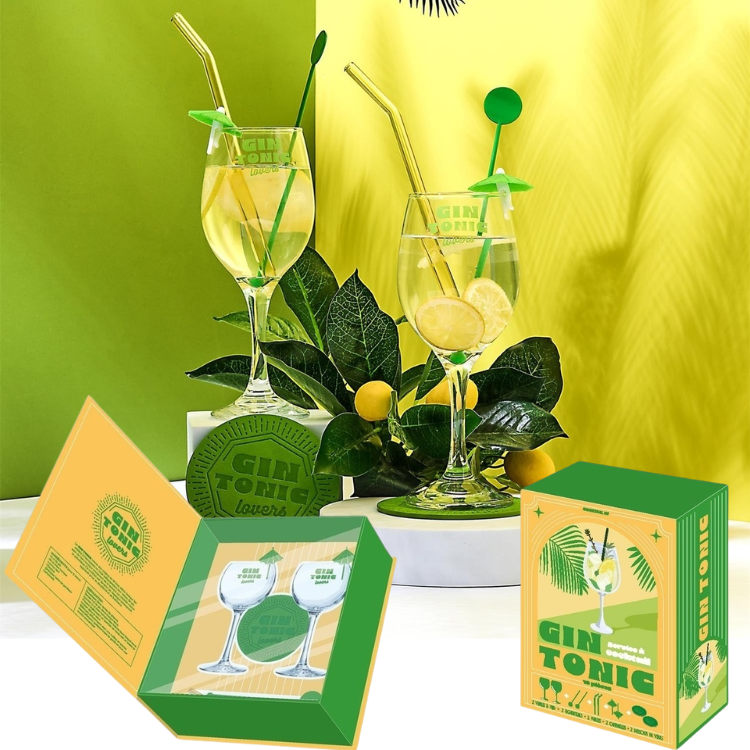 Two gin and tonic glasses with lemon slices and green straws surrounded by citrus leaves and branded packaging