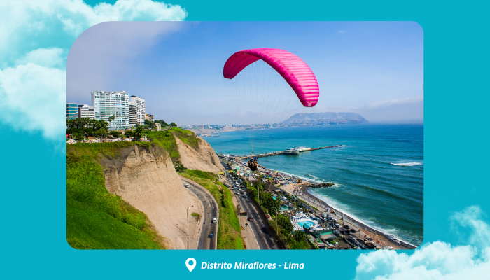 Paraglider with bright pink canopy over Miraflores cliffs and coastal road, overlooking Lima’s shoreline and the Pacific Ocean