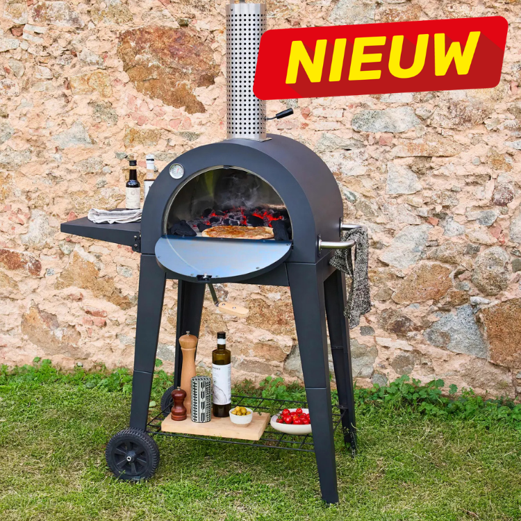 Portable charcoal pizza oven with glowing coals and pizza, chimney and wheels on grass against stone wall, bottles, condiments