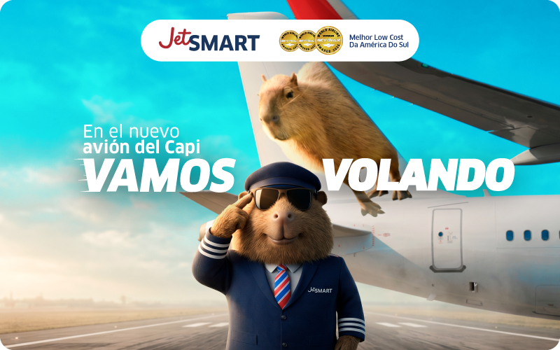 JetSMART ad showing a capybara pilot in uniform saluting beside an aeroplane with another capybara on the wing, bright sky