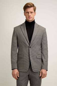 Man wearing grey pinstripe suit and black turtleneck, standing against plain light background, front view