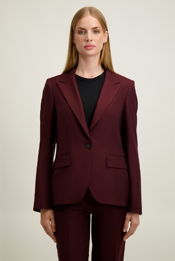 Woman wearing tailored burgundy blazer and matching trousers with a black top, neutral studio background