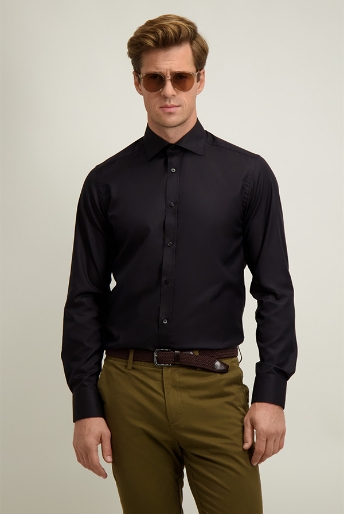 Man in fitted black long-sleeve shirt, khaki trousers, brown belt and sunglasses against plain light studio background