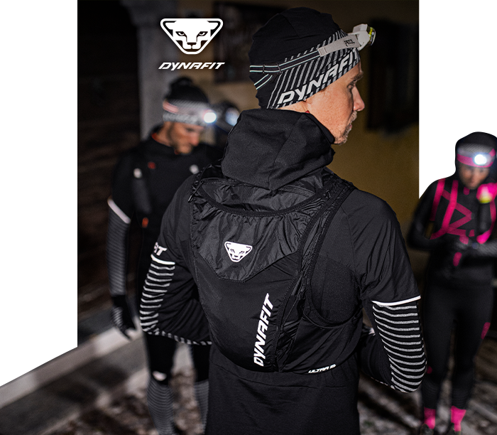 Three night-time trail runners in Dynafit gear with headlamps, focus on runner wearing a Dynafit backpack displaying the logo