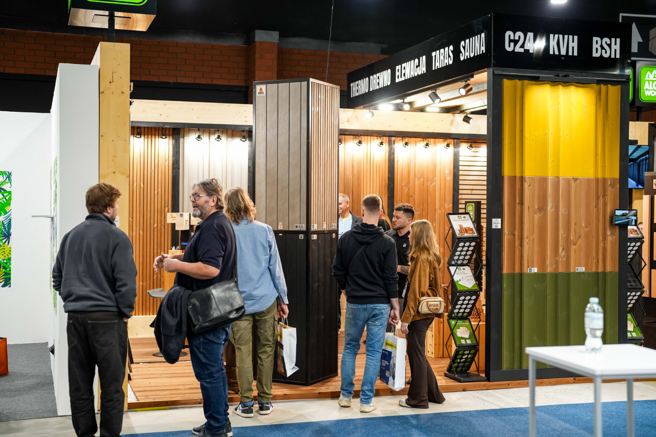 Group of visitors touring a timber cladding and sauna materials exhibition stand at a building trade show