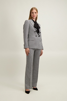 Full-length photo of woman in a grey checked double-breasted suit with a black bow blouse and black heels