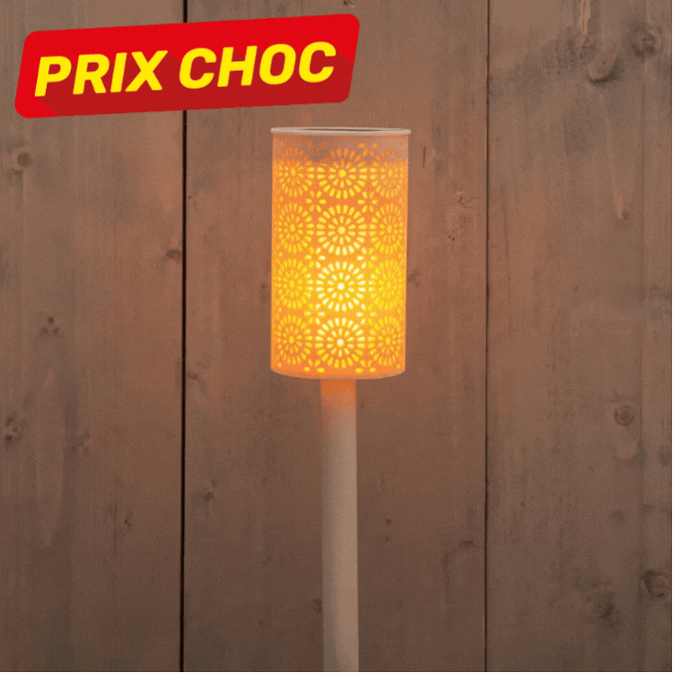 Three decorative outdoor solar stake lights with cut-out floral metal shades glowing warm against a wooden fence