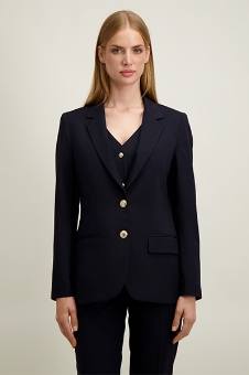 Front-facing model wearing a navy tailored blazer with gold buttons and matching trousers on a neutral background