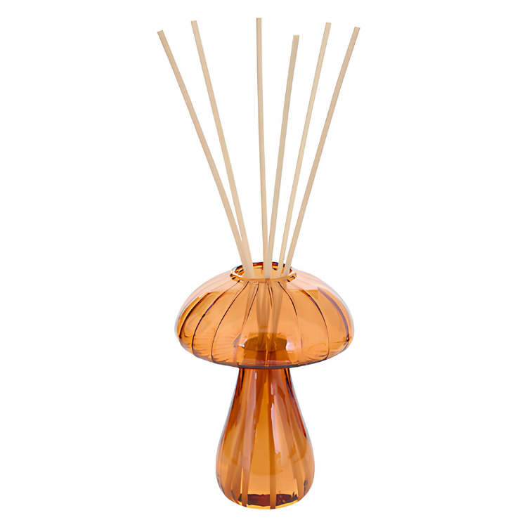 Amber glass mushroom-shaped reed diffuser with slender natural rattan sticks on white background