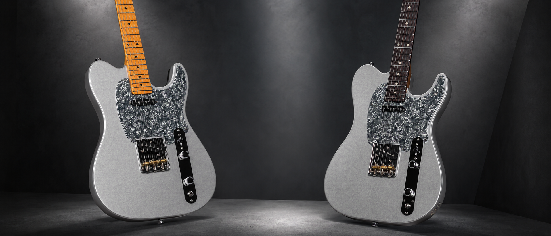 Two silver Telecaster-style electric guitars with pearloid pickguards and maple and rosewood necks on a dark spotlighted studio floor