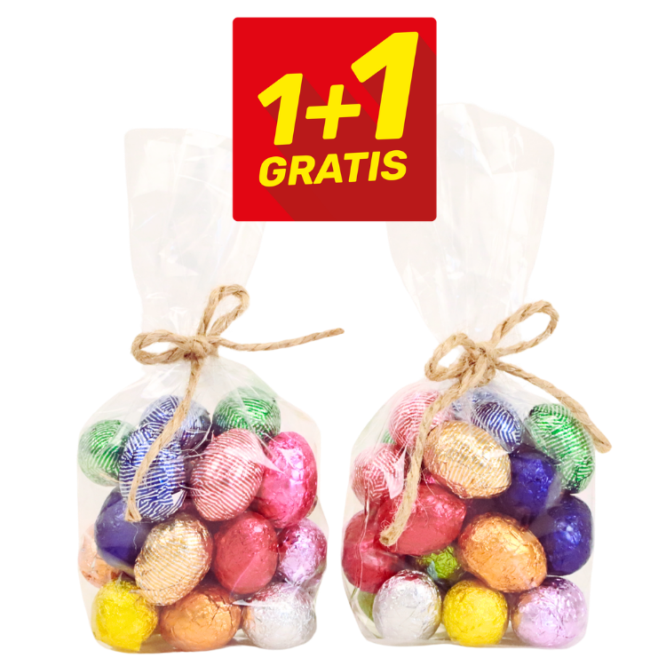 Two clear cellophane bags of colourful foil-wrapped chocolate Easter eggs tied with twine, with a red '1+1 GRATIS' promotional badge