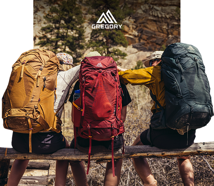 Three hikers sitting on a wooden bench wearing large yellow, red and green Gregory backpacks in a rocky outdoors