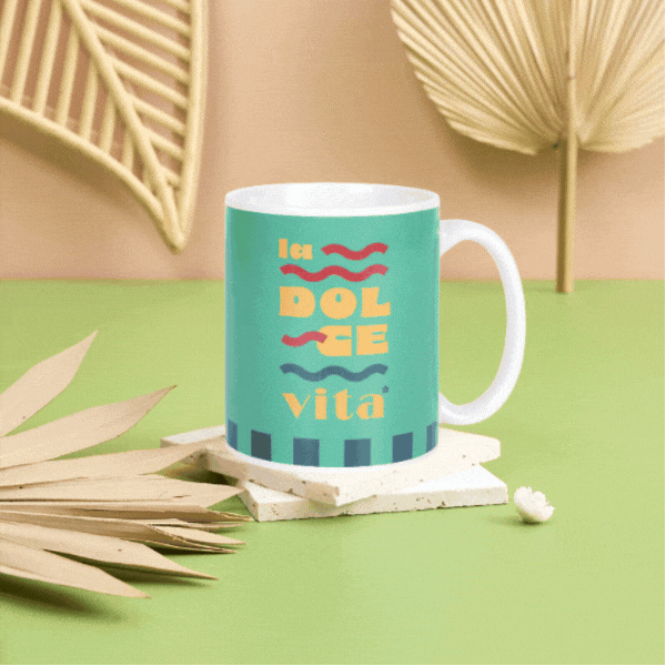 Four colourful ceramic mugs with summer phrases (La Dolce Vita, Qué Calor, Ciao Bella, Oh Sole Mi) on coasters on a green surface with decorative palm leaves