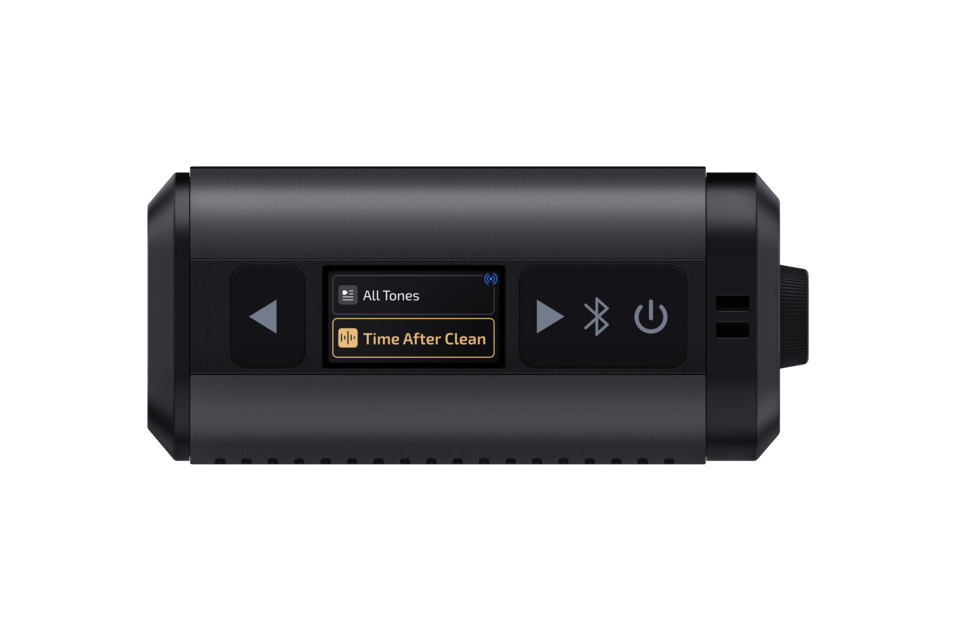 Black compact Bluetooth speaker with central colour display showing ‘All Tones’ and ‘Time After Clean’, play, Bluetooth and power buttons