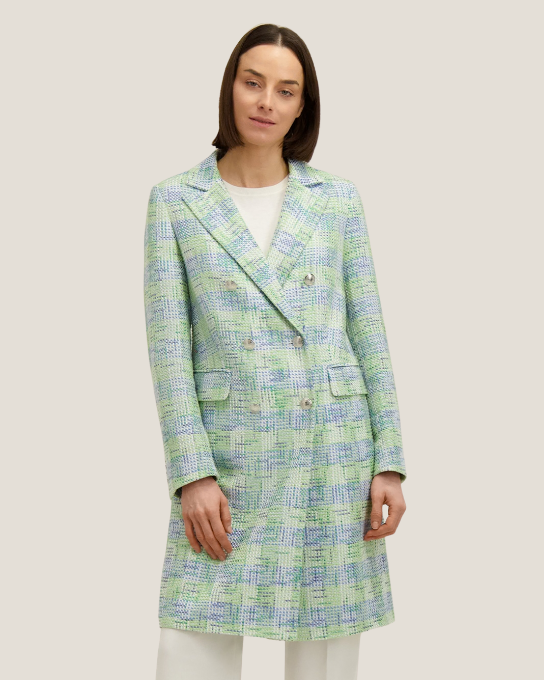 Model wearing a pastel green and blue checked tweed double-breasted knee-length coat over white top and trousers